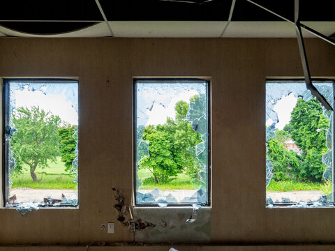 trois fenêtres dans un immeuble abandonné avec vue sur des arbres en été