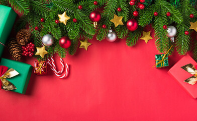 Christmas background presents greeting card with top view overhead green fir tree branches and decoration gift box, Xmas holiday celebration season on red table background with copy space