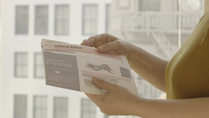 Side view unidentified woman putting an official election ballot into an envelope for the November 2020 United States local and federal elections. Slow motion, recorded in 4K UHD at 120fps
