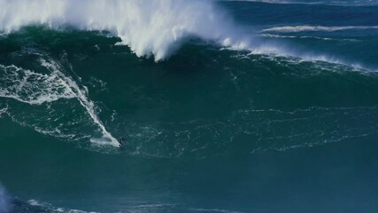 Slow motion of a big wave surfer riding a crazy big monster wave in Nazaré, Portugal. Nazaré is a small village in Portugal with the biggest waves in the world.