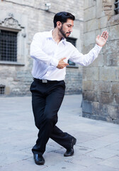 Handsome passionate man dancing alone outdoors against old stone castle