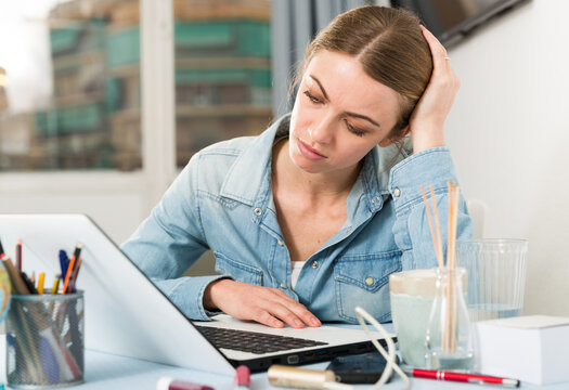 Upset young woman counts family budget on laptop. High quality photo