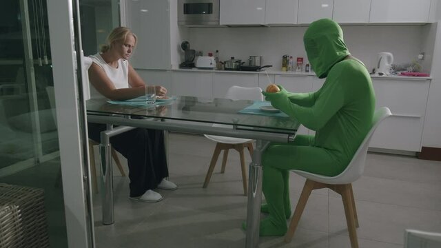 Man wearing a green costume and sitting at the table at home. Communication troubles with his wife