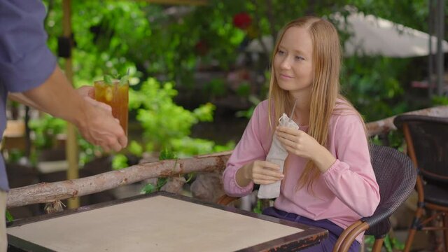 In a cafe, a young woman uses her own reusable metallic straws instead of a single-use plastic drinking straw. Concept of reducing the use single plastic