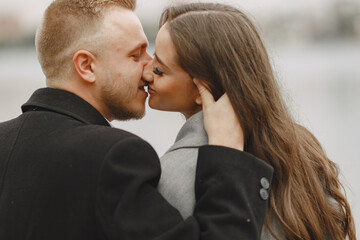 Cute couple in a park. Lady in a gray coat. People on the pier.