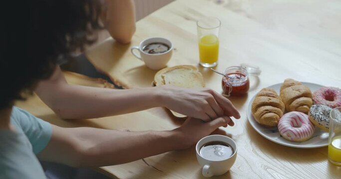 Close up of ay couple holding hands holding hands having breakfast together