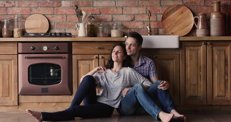 Couple in love relaxing sit on warm floor with underfloor heat system stay at home on weekend. Romantic harmonic relations, bank loan for family, happy clients of kitchen remodelling services concept
