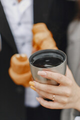 Cute couple in a park. Lady in a gray coat. People with a thermos and croissant.