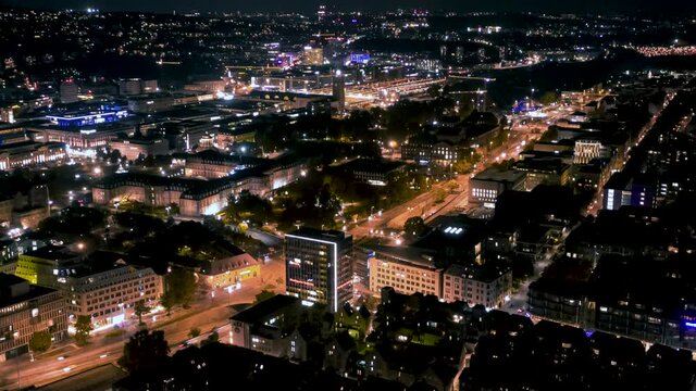 Aerial night time lapse in 4k of downtown city skyline in Stuttgart, Germany  spinning and panning down.