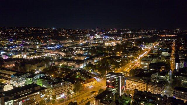 Moving aerial night time lapse in 4k of downtown skyline in the city of Stuttgart, Germany  from left to right.