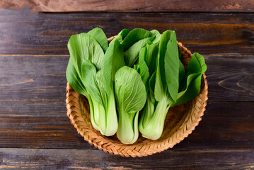 Fresh Bok Choy or Pak Choi (Chinese cabbage) in bamboo basket on wooden background, Organic vegetables, Top view