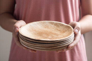Hand holding Betel palm leaf plate (Biodegradable, Compostable or Eco friendly disposable plate),...