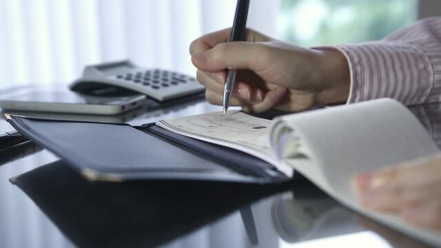 Businesswoman writing a cheque in office