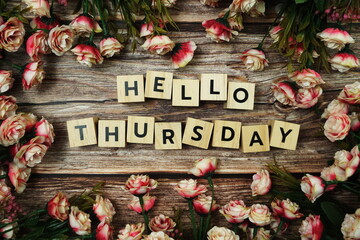 Hello Thursday alphabet letter with Blooming flower on wooden background