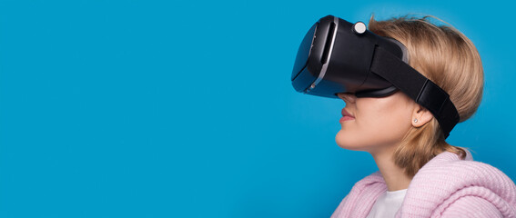 Caucasian woman with vr headset is posing on a blue studio wall with free space