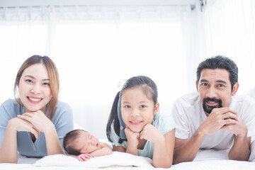 happy family mother, father and children laughing, playing and smiling in bed in bedroom at home. a young family with young children to bed in the bedroom.