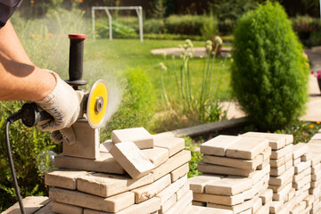 Fototapeta premium Master saws paving slabs with a grinder grinder. Dust. .