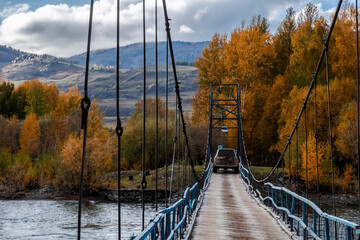 Obraz premium Offroad suv cross the river through vintage rustic suspension bridge. River crossing concept. Old rope bridge. Travel, journey, adventure concept.