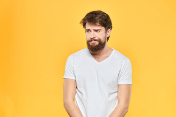 Obraz premium Bearded man in a white T-shirt gestures with his hands emotions studio yellow background