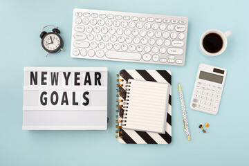 New year goals text on lightbox with office accessories