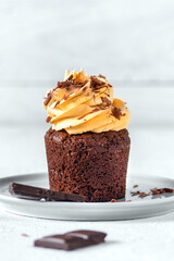 Chocolate cupcakes with pumpkin cream on light background