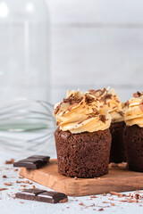 Chocolate cupcakes with pumpkin cream on light background