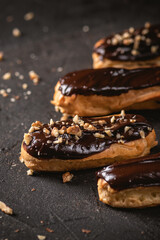 Chocolate eclairs filled with cream on dark background