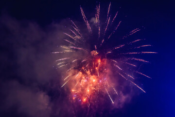 Beautiful colorful holiday fireworks in the evening sky with majestic clouds