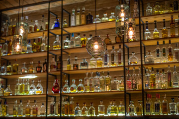 Fototapeta na wymiar Defocused background of bar counter with various bottles of alcohol.