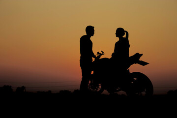 Couples with a motorcycle at sunset.