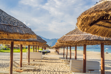Fototapeta na wymiar Beach with thatched umbrellas and wooden loungers