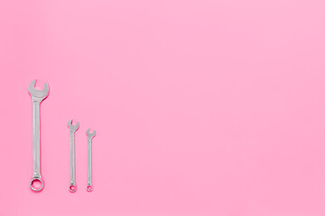 Three metal wrenches of different sizes isolated on pink background with copy space. Conceptual idea of the differences between: boss and employee, older and younger, big and small, parent and child