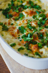 Top view of a traditional pumpkin pie with turkey and baked vegetables in a white dish on a wooden board.