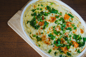 Top view of a traditional pumpkin pie with turkey and baked vegetables in a white dish on a wooden board.