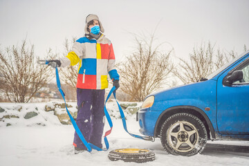 Man with towing rope hooks near towed car. wear medical masks due to the COVID-19 coronavirus