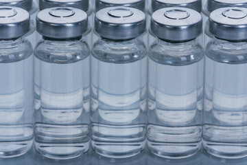 Glass medical ampoule vial for injection. Medicine is dry white drug penicillin powder or liquid with of aqueous solution in ampulla. Close up. Bottles ampule with aluminum cap on backgrounds gray.