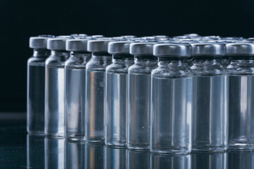 Glass medical ampoule vial for injection. Medicine is dry white drug penicillin powder or liquid with of aqueous solution in ampulla. Close up. Bottles ampule with aluminum cap on backgrounds gray.