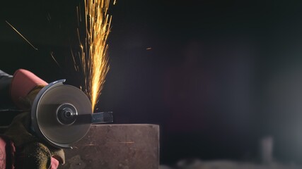 Forge workshop. Smithy manual production. Close up details of sparks, industrial worker using angle grinder and cutting steel. The blacksmith makes iron products for manufacture of fireplaces, stoves.