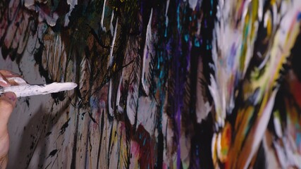 Artist designer draws an eagle on the wall. Craftsman decorator paints a picture with acrylic oil color brush. Close-up dark magic cinematic look. Painter dressed in a paint coat. Indoor.