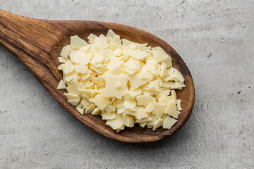 Grated white chocolate. Chocolate flakes in wooden spoon.
