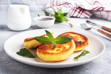 Fritters of cottage cheese with mint. Cheese curd cheesecakes, pancakes on a grey concrete background