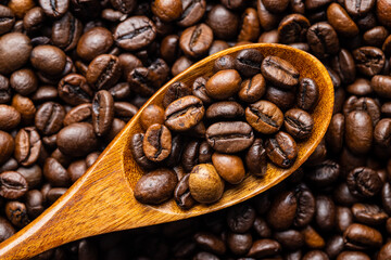 Mixed coffee beans in wooden spoon. Arabica and robusta.