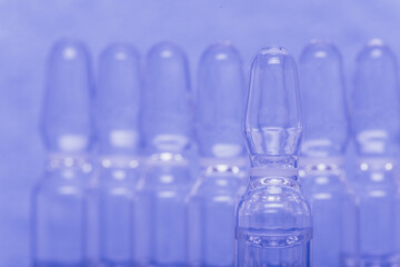 Glass medical ampoule vial for injection. Medicine is liquid sodium chloride with of aqueous solution in ampulla. Close up. Bottles ampule multicolor on background color and water. Human plasma.