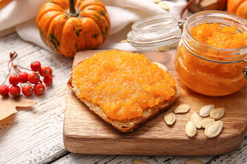 Jar of tasty pumpkin jam and bread on table