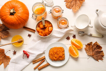 Autumn composition with tasty pumpkin jam on white wooden background