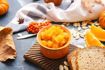 Tasty pumpkin jam with bread on color background