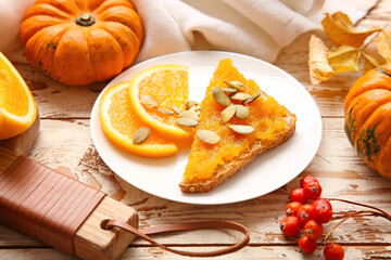 Tasty pumpkin jam with bread and orange fruit on table