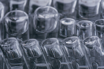 Glass medical ampoule vial for injection. Medicine is liquid sodium chloride with of aqueous solution in ampulla. Close up. Bottles ampule multicolor on background color and water. Human plasma.