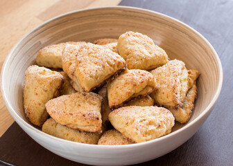 Cottage cheese triangular cookies in a plate on a wooden background