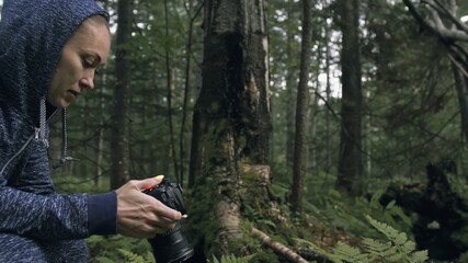 Traveler photographing scenic view in forest. One caucasian woman shooting nice magic look. Girl take photo video on dslr mirrorless camera. Professional photographer travel with backpack. Outdoor.
